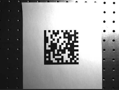 Data Matrix code printed on paper in front of a perforated metal plate